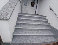 Hellgraue Treppe mit 6 Stufen führt zu weißer Haustür.
