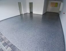Große Garage mit weißen Wänden, graumelierten Garagenboden und 3 Durchgängen.