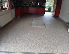 Garagenbodenbeschichtung beige in Werkstatt mit rot-schwarzen Schränken.