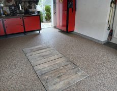 Garagenbodenbeschichtung beige in Werkstatt mit rot-schwarzen Schränken.