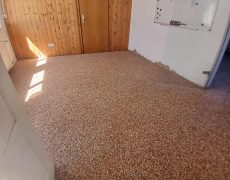 Raum mit Holzwand und -tür mit braunem Steinteppichboden.