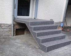 Seitliche Ansicht von dunkelgrau melierter Treppe mit 5 Stufen mit Hohlraum darunter vor Terrassentür.