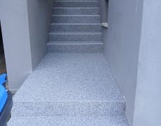Hellgraue Treppe zwischen zwei grauen Mauern vorn Haustür.