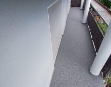 Länglicher Balkon ohne Geländer mit zwei Balkontüren und Baugerüst.